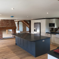Blue and white kitchen with brick fire place and wooden staircase in Lakenheath