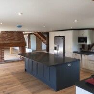 Blue and white kitchen with brick fire place and wooden staircase in Lakenheath